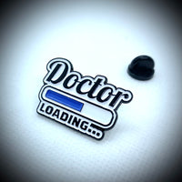 An enamel pin saying Doctor loading…